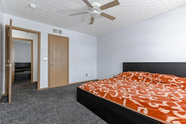 bedroom with a textured ceiling, dark carpet, and ceiling fan