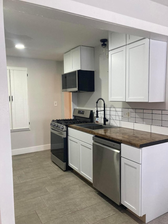 kitchen with sink, wooden counters, decorative backsplash, white cabinets, and appliances with stainless steel finishes