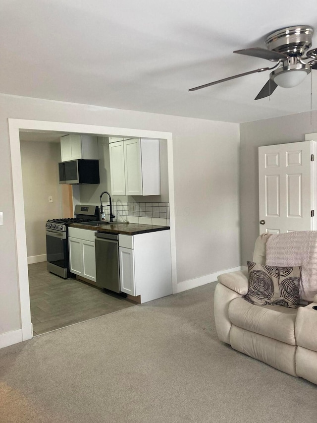 kitchen featuring carpet flooring, tasteful backsplash, stainless steel appliances, sink, and white cabinetry