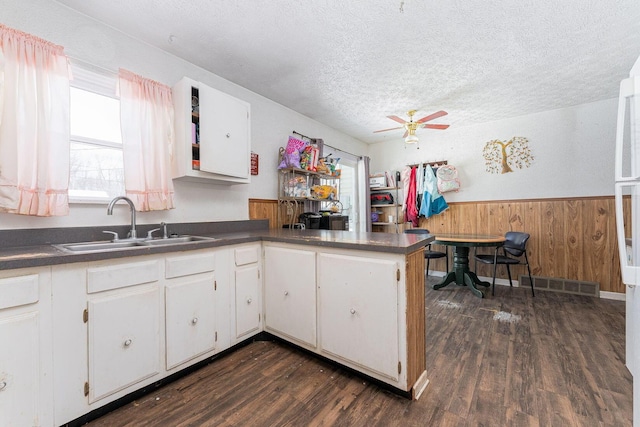 kitchen with white cabinets, dark hardwood / wood-style flooring, a textured ceiling, and wooden walls