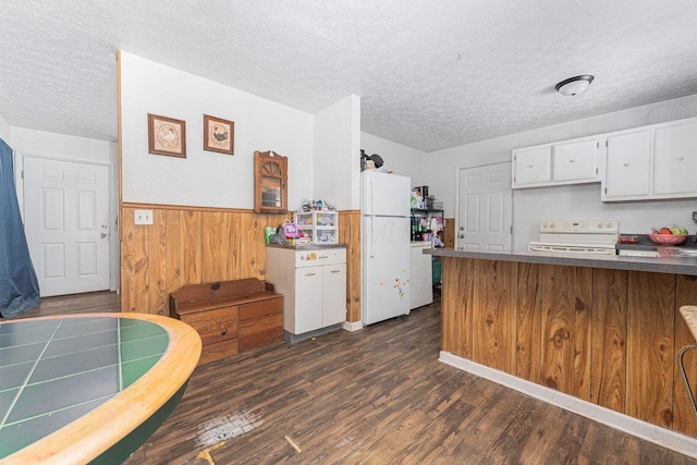 kitchen with white cabinetry, white fridge, a textured ceiling, wooden walls, and range