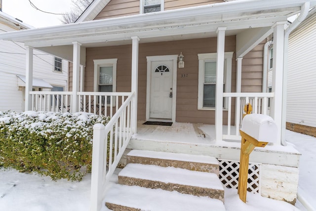 snow covered property entrance with a porch