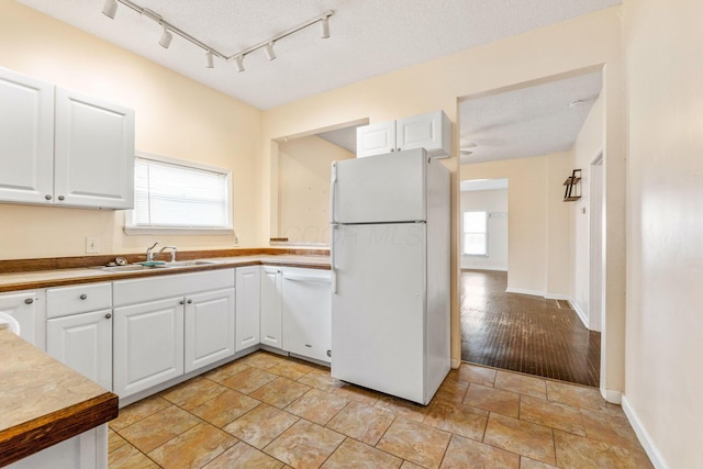 kitchen featuring a textured ceiling, white cabinetry, sink, and white appliances