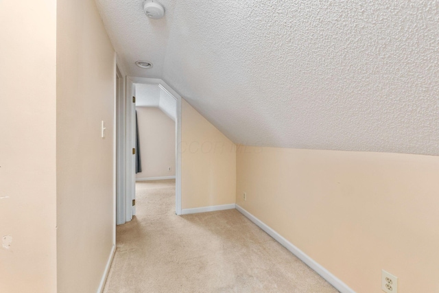 bonus room with light colored carpet, lofted ceiling, and a textured ceiling