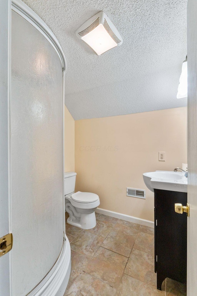 bathroom with an enclosed shower, vanity, toilet, and vaulted ceiling