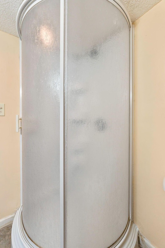 bathroom with a shower with shower door and a textured ceiling