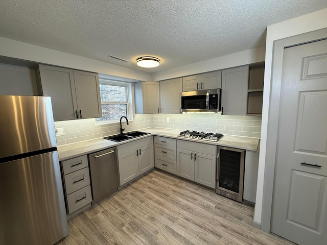 kitchen featuring tasteful backsplash, wine cooler, sink, and appliances with stainless steel finishes