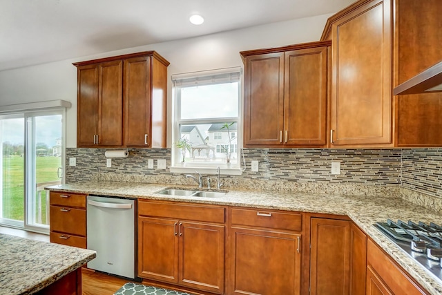 kitchen featuring light stone countertops, tasteful backsplash, stainless steel appliances, sink, and light hardwood / wood-style flooring