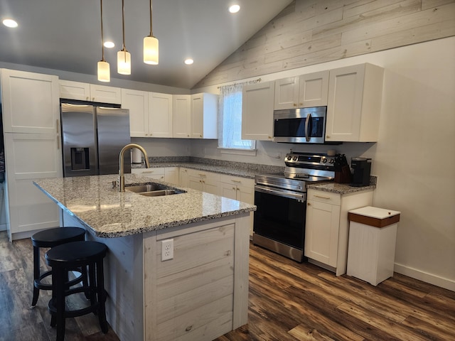 kitchen featuring white cabinetry, sink, stainless steel appliances, lofted ceiling, and a kitchen island with sink