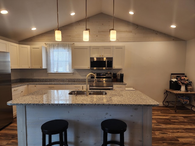 kitchen featuring light stone countertops, appliances with stainless steel finishes, white cabinetry, and pendant lighting