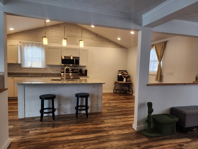 kitchen with white cabinetry, sink, light stone counters, pendant lighting, and appliances with stainless steel finishes
