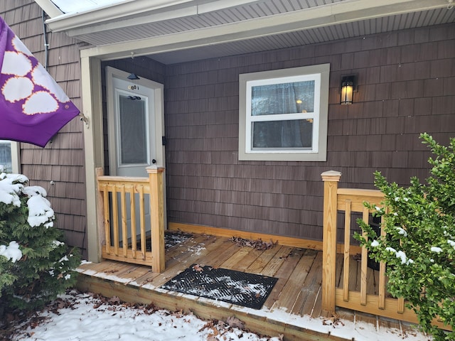 snow covered property entrance featuring a deck