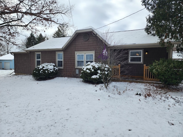 snow covered rear of property with a garage and an outbuilding