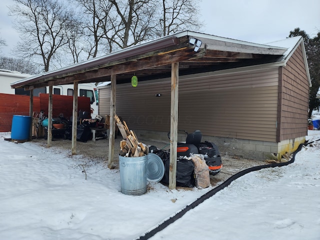 snow covered parking area with a carport