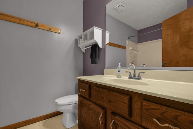 bathroom with a textured ceiling, vanity, and toilet