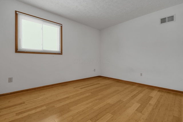 unfurnished room with light wood-type flooring and a textured ceiling