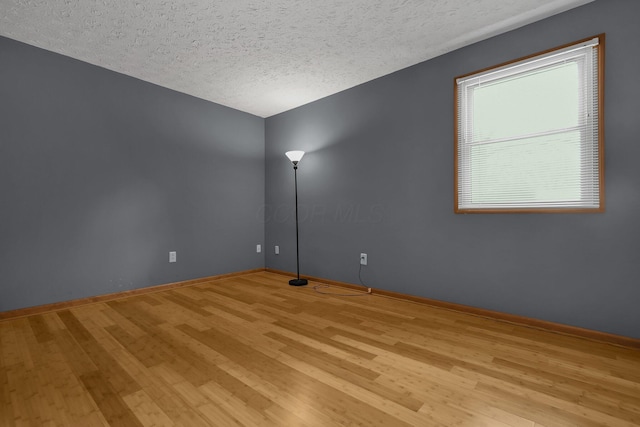 empty room with a healthy amount of sunlight, a textured ceiling, and light hardwood / wood-style flooring