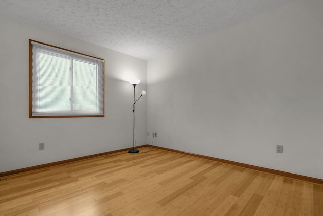 spare room with light hardwood / wood-style flooring and a textured ceiling