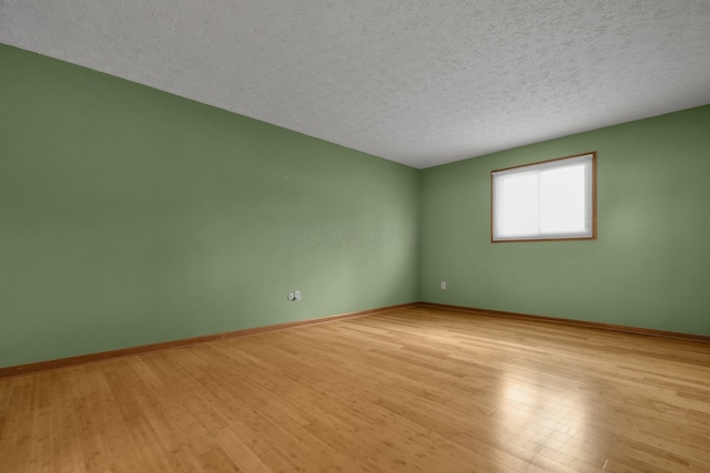 empty room featuring a textured ceiling and light hardwood / wood-style flooring