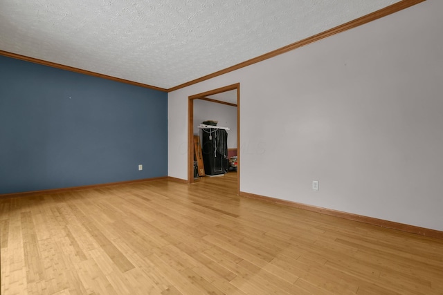 empty room featuring crown molding, light wood-type flooring, and a textured ceiling