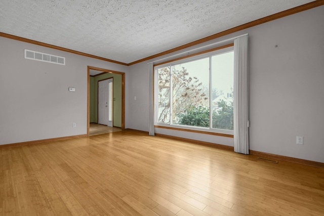 empty room featuring ornamental molding, a textured ceiling, and light wood-type flooring