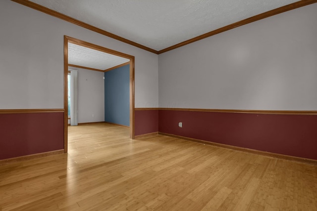 unfurnished room with a textured ceiling, light wood-type flooring, and crown molding