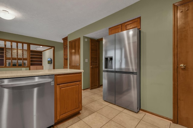 kitchen with light tile patterned floors, a textured ceiling, and appliances with stainless steel finishes