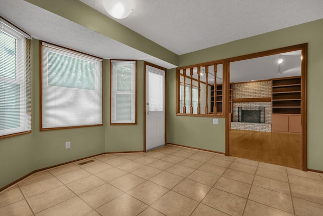 unfurnished living room featuring built in shelves, a fireplace, light tile patterned flooring, and a textured ceiling