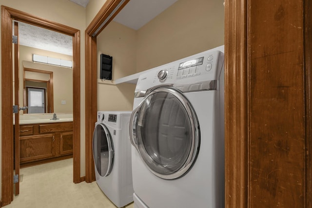 laundry room featuring separate washer and dryer, sink, and a textured ceiling