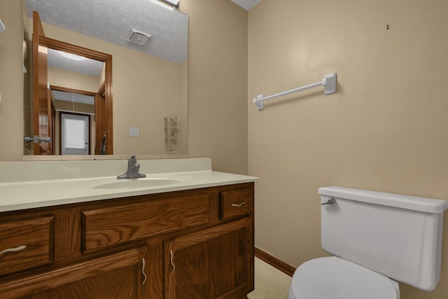 bathroom with vanity, toilet, and a textured ceiling