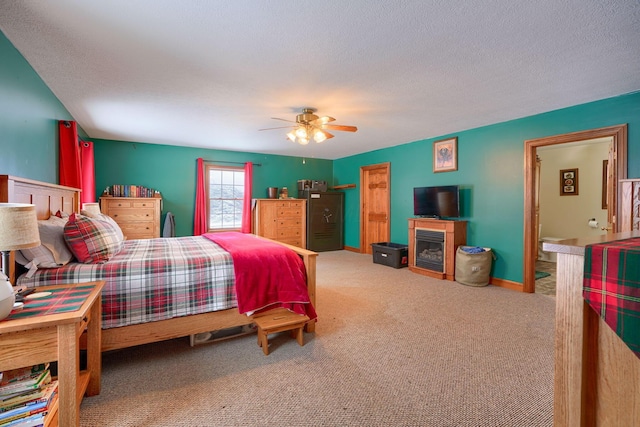 carpeted bedroom with a textured ceiling, ceiling fan, and a fireplace