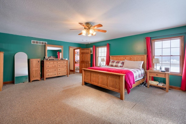 carpeted bedroom with ceiling fan and a textured ceiling