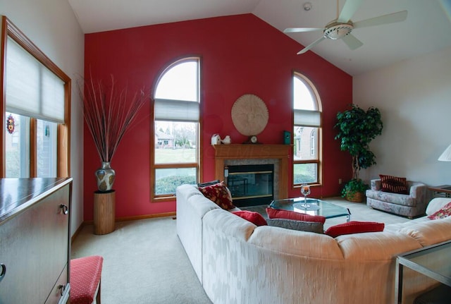 living room with high vaulted ceiling, ceiling fan, light colored carpet, and a high end fireplace