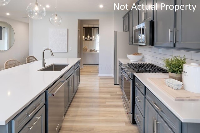 kitchen with sink, hanging light fixtures, gray cabinets, and stainless steel appliances