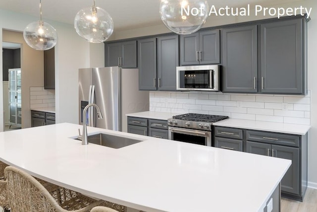 kitchen with sink, backsplash, stainless steel appliances, and a kitchen island with sink