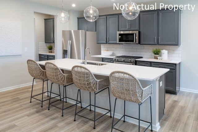 kitchen with stainless steel appliances, sink, tasteful backsplash, and a kitchen island with sink