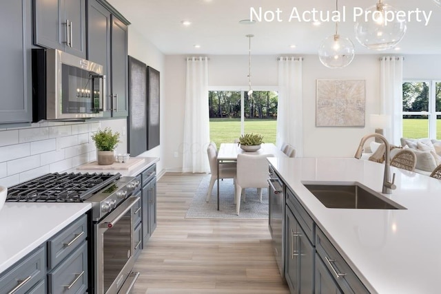 kitchen with stainless steel appliances, decorative backsplash, plenty of natural light, pendant lighting, and sink