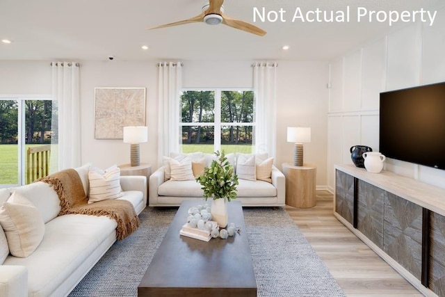 living room featuring ceiling fan, plenty of natural light, and light hardwood / wood-style flooring