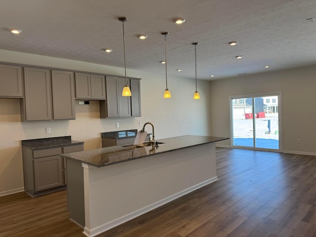 kitchen with sink, pendant lighting, gray cabinets, and dark stone countertops