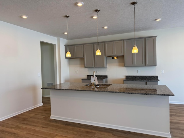 kitchen featuring dark stone counters and an island with sink