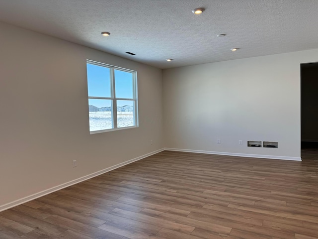 empty room featuring a textured ceiling, a mountain view, and hardwood / wood-style flooring