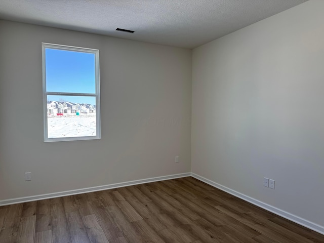 spare room featuring hardwood / wood-style floors and a textured ceiling