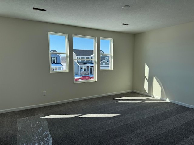 empty room with dark carpet and a textured ceiling