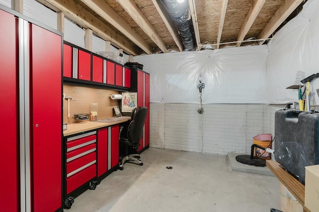 basement featuring a workshop area and brick wall