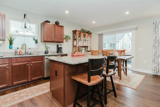 kitchen with a kitchen bar, sink, dishwasher, a center island, and dark hardwood / wood-style floors