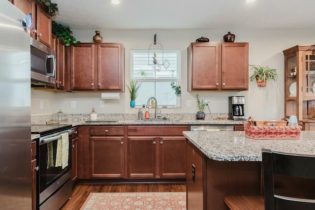 kitchen featuring pendant lighting, sink, light stone countertops, appliances with stainless steel finishes, and dark hardwood / wood-style flooring