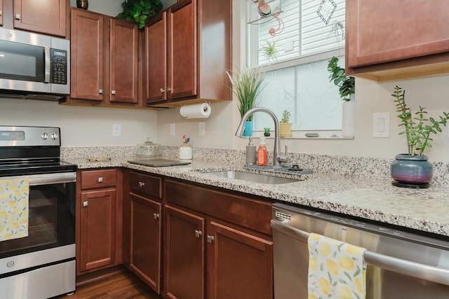 kitchen with light stone counters, sink, stainless steel appliances, and dark hardwood / wood-style floors