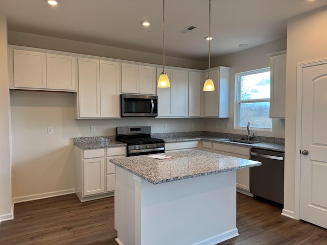 kitchen with a sink, visible vents, white cabinets, appliances with stainless steel finishes, and a center island