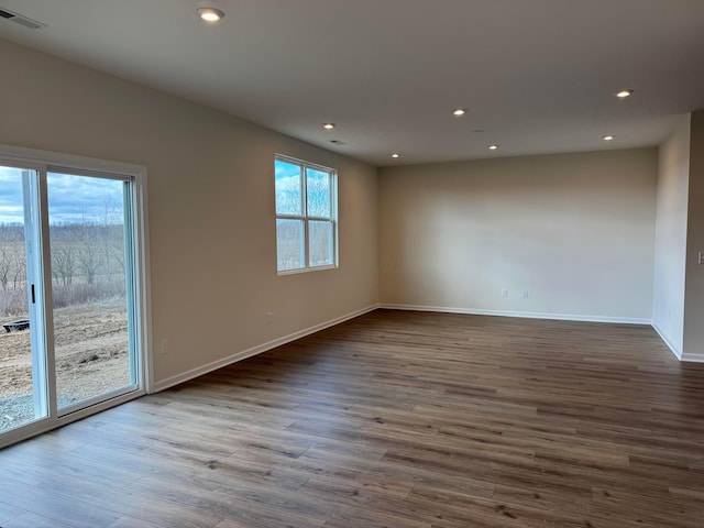 empty room featuring dark wood-style floors, recessed lighting, visible vents, and baseboards