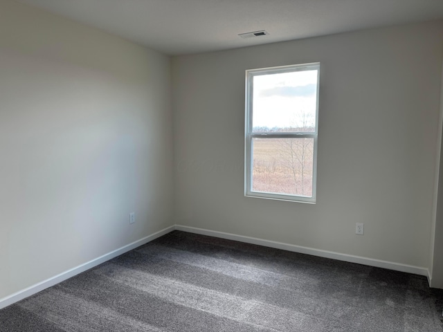 unfurnished room featuring baseboards, visible vents, and dark carpet